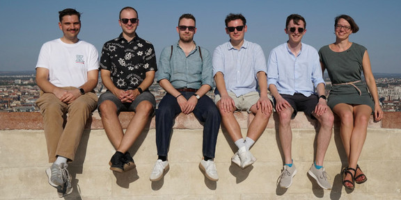 5 men and 1 woman sitting on a wall. 