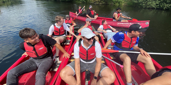 Group Photo of 5 Canoes in the river with several people